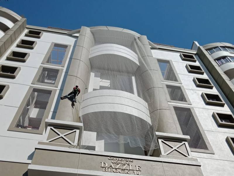 Technician installing a duct area safety net across the open duct of an apartment block